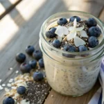 close-up of no sugar overnight oats in a glass jar topped with fresh berries and coconut