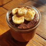 chocolate sugar free overnight oats in a glass jar topped with banana and cocoa powder